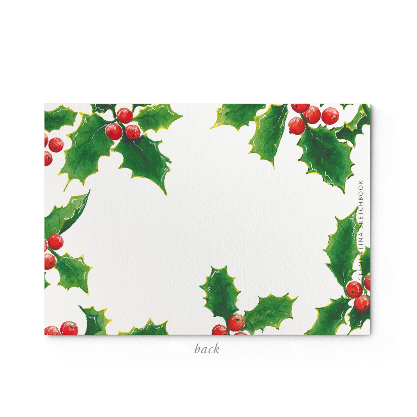 Image shows the back of a Clementina Sketchbook Christmas stationery card, with a holly watercolour design and a dark green border.