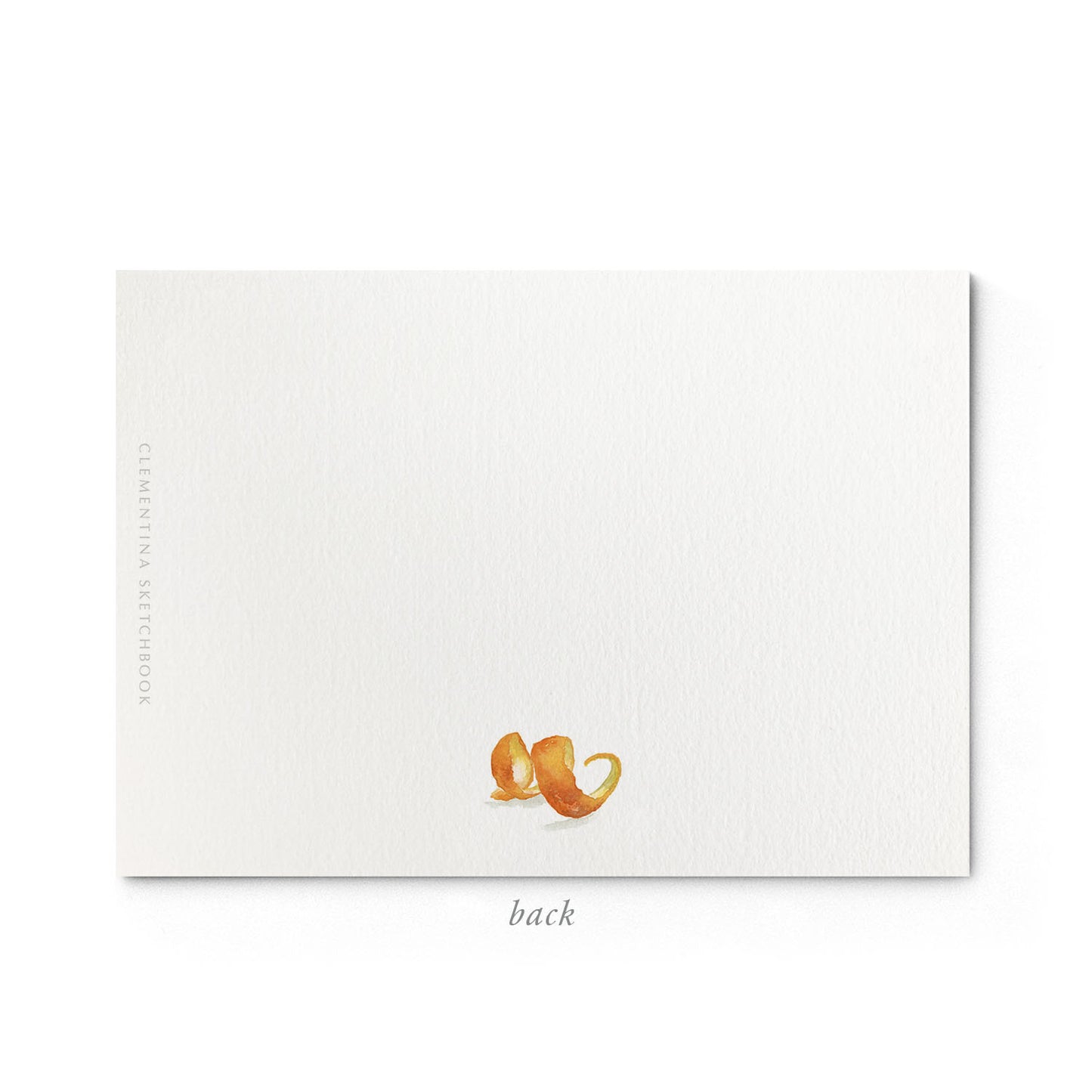 Image shows the back of a Clementina Sketchbook clementine stationery card, with fruit watercolour design and a green ribbon border.
