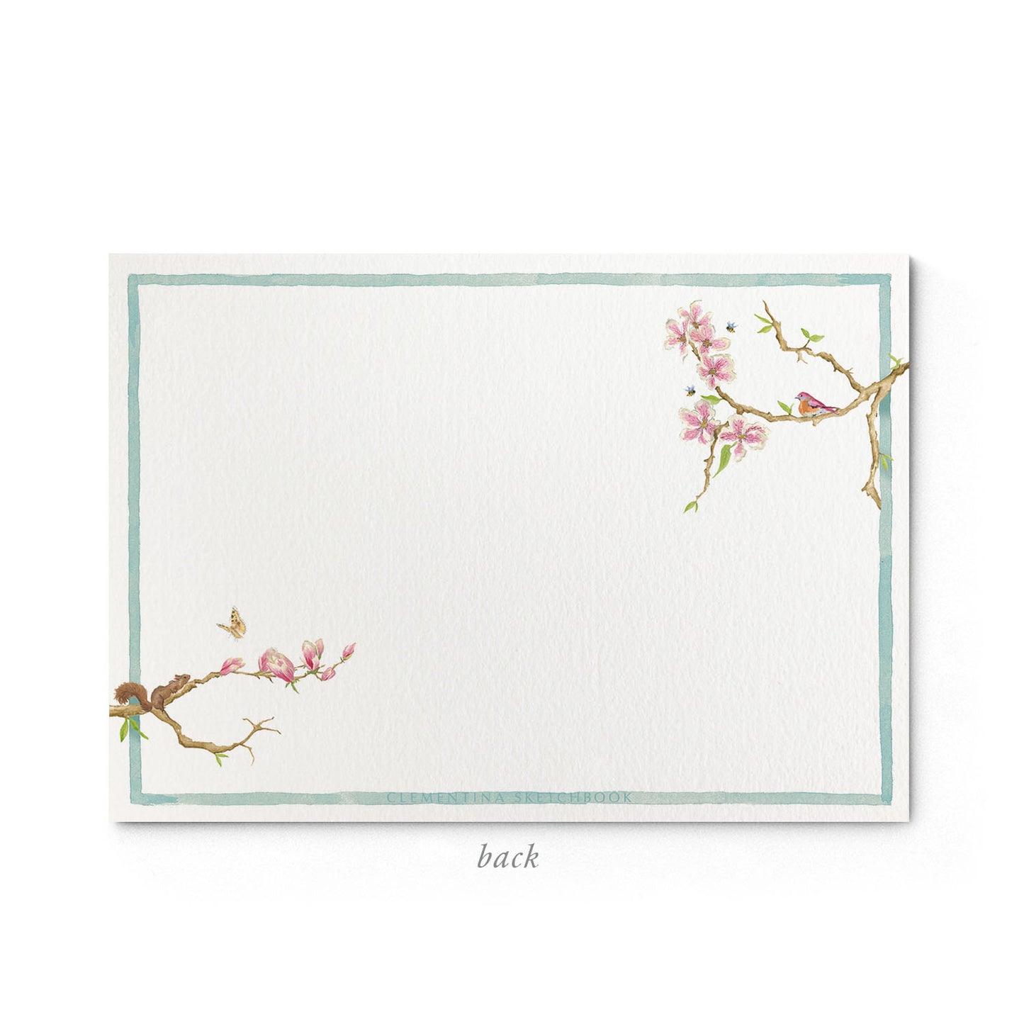 Image shows the back of a Clementina Sketchbook floral stationery card, with a magnolia watercolour design and a blue border.