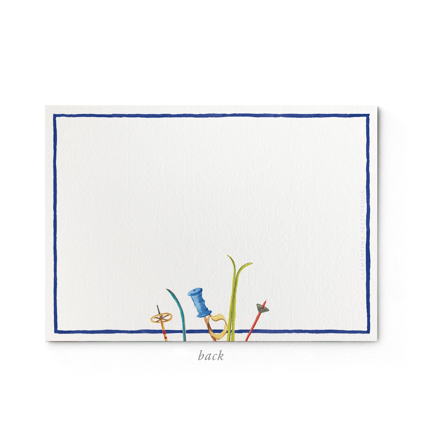 Image shows the back of a Clementina Sketchbook Christmas stationery card, with a skis watercolour design and a blue border.