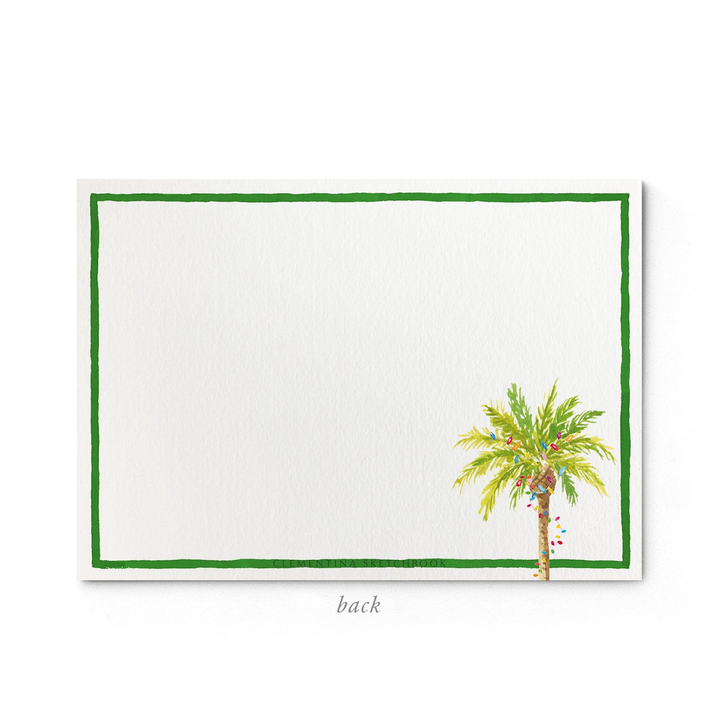 Image shows the back of a Clementina Sketchbook tropical stationery card, with a palm tree watercolour design and a green border.