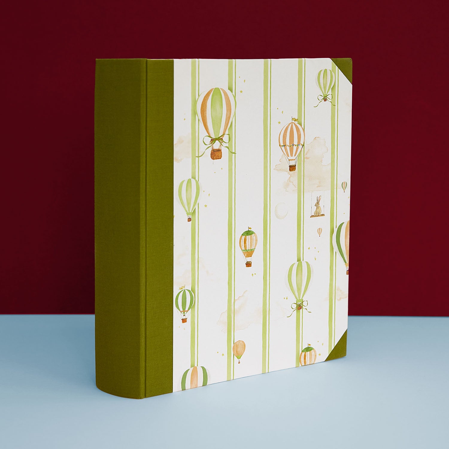 Image of the hot air balloon baby book bundle in green, featuring hand-painted watercolour designs.                                                                                                         Image of the hot air balloon baby book bundle in blue, featuring hand-painted watercolour designs.      