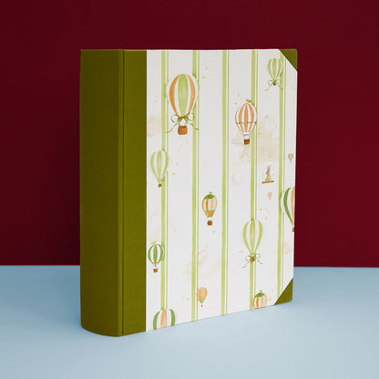 Image of the hot air balloon baby book bundle in green, featuring hand-painted watercolour designs.                                                                                                         Image of the hot air balloon baby book bundle in blue, featuring hand-painted watercolour designs.      