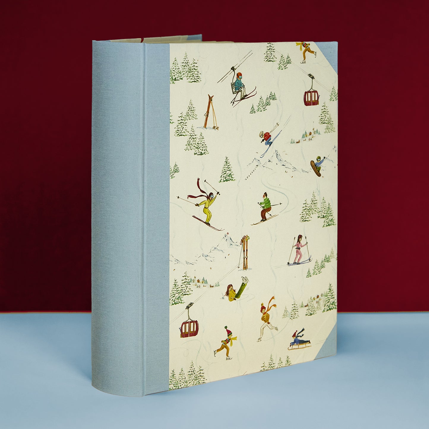 Light blue Mountain Activities family photo album with skiing scenes, handmade in Italy, part of Clementina’s personalised photo albums.