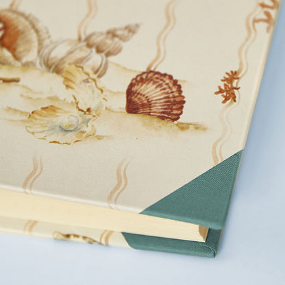 Detail of Shells on Shells memory book corner with turquoise binding, seashell illustration, personalised wedding photo album option.